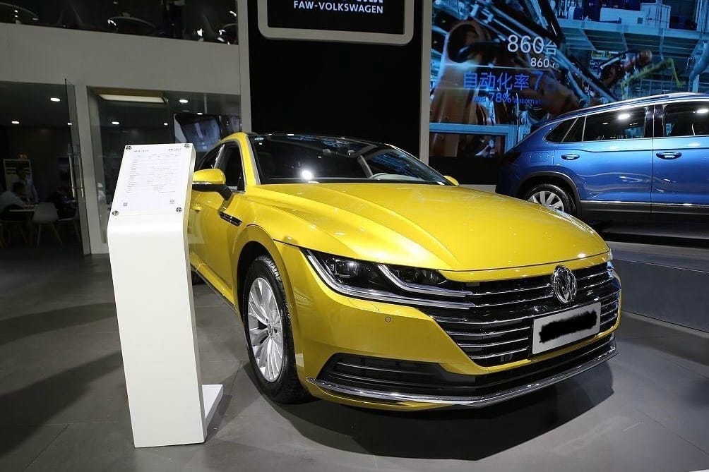 Front view of a yellow Volkswagen Arteon on display at an auto show
