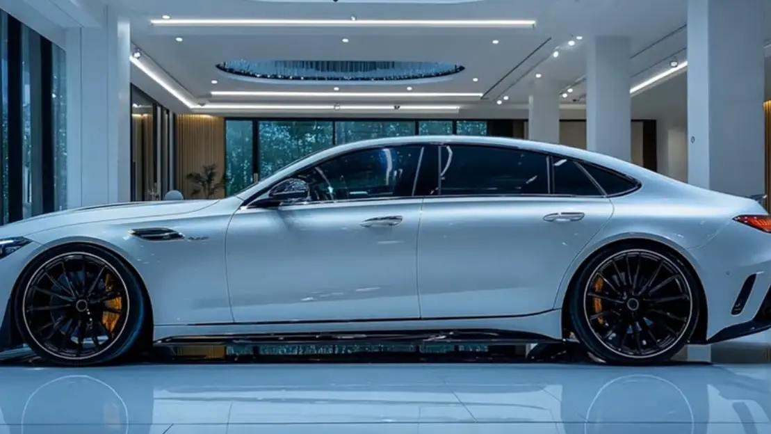 Side profile of a white Mercedes-Benz luxury sedan with black alloy wheels, displayed in a modern showroom