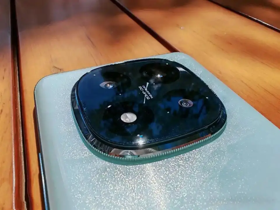 Close-up of the Redmi Note 15 Pro's glossy triple-camera setup with 50MP OIS branding, showcasing its flagship-style design on a sparkly blue back panel.