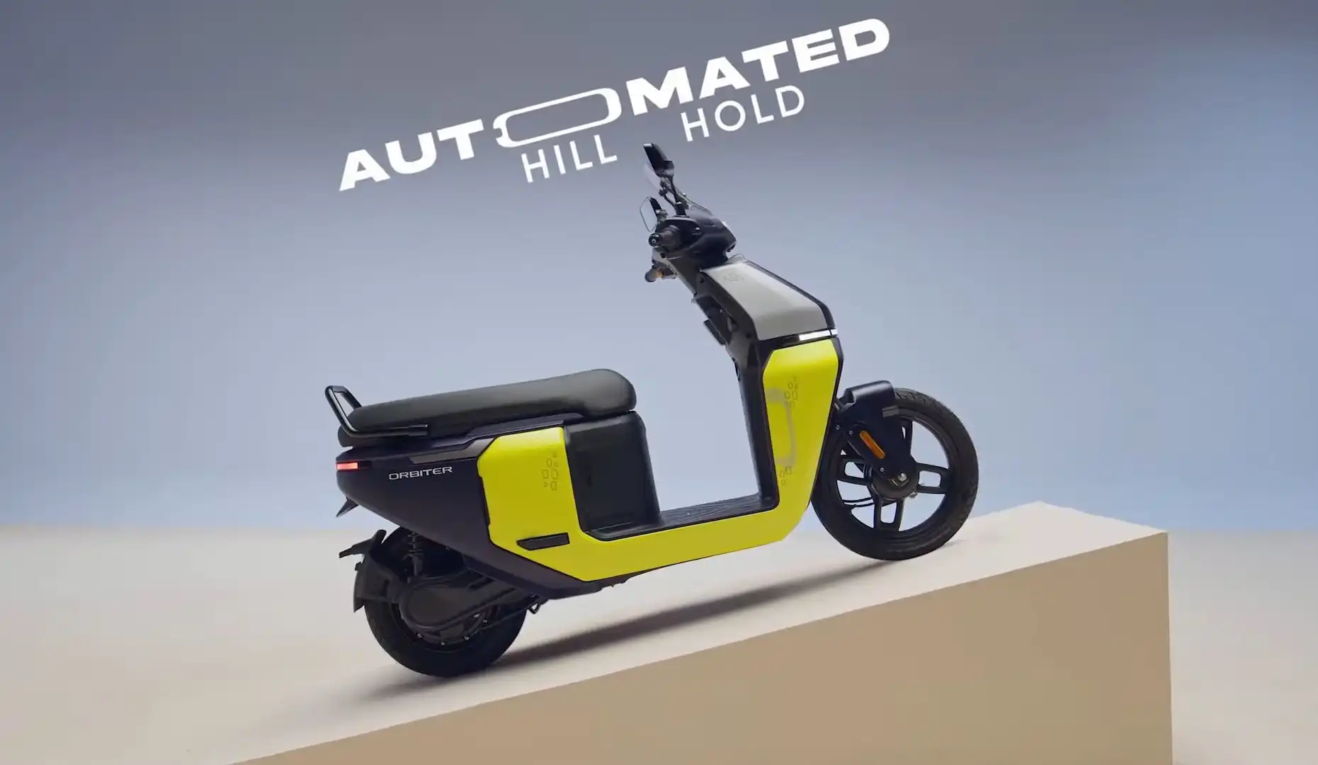 A neon yellow and black TVS Orbiter electric scooter is shown on a ramp,
demonstrating its automated hill hold feature.