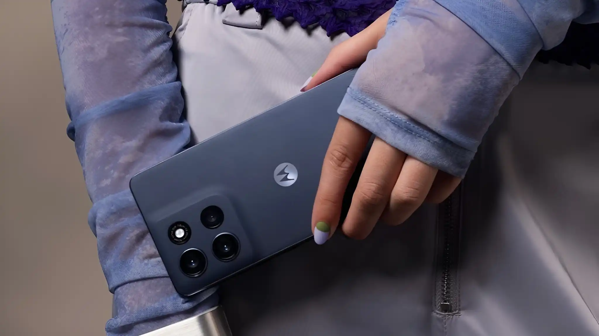 A hand with painted nails holds a dark blue Motorola Moto G86 5G, highlighting its camera array and sleek design.