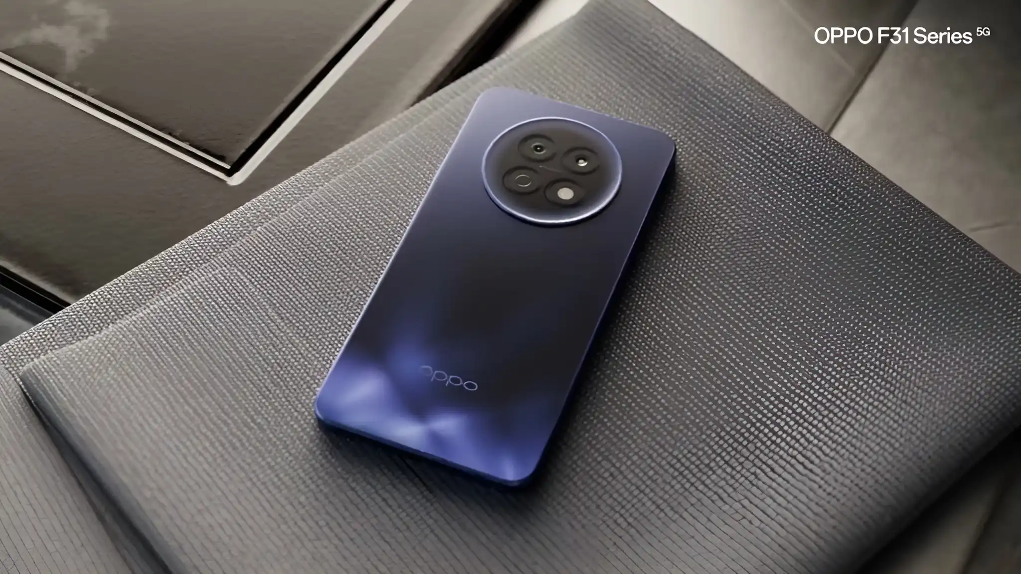 Oppo F31 Pro plus smartphone in blue with circular rear camera module placed on textured surface, showcasing premium design.