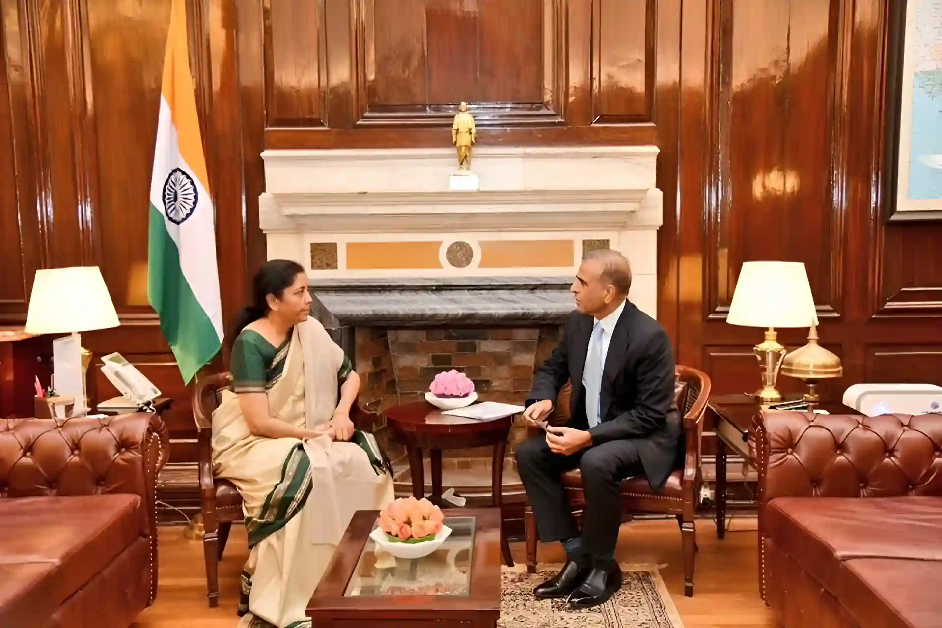 Two people in formal meeting with Indian flag in background